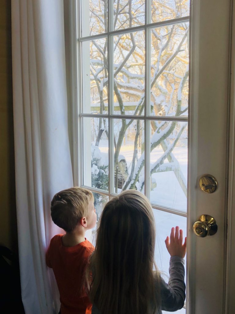 kids looking out the door at new snow