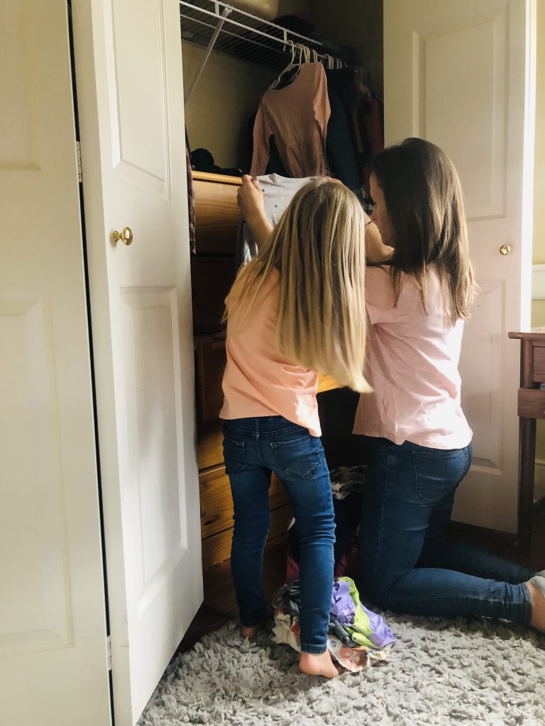 mom and girl sorting clothes by a closet