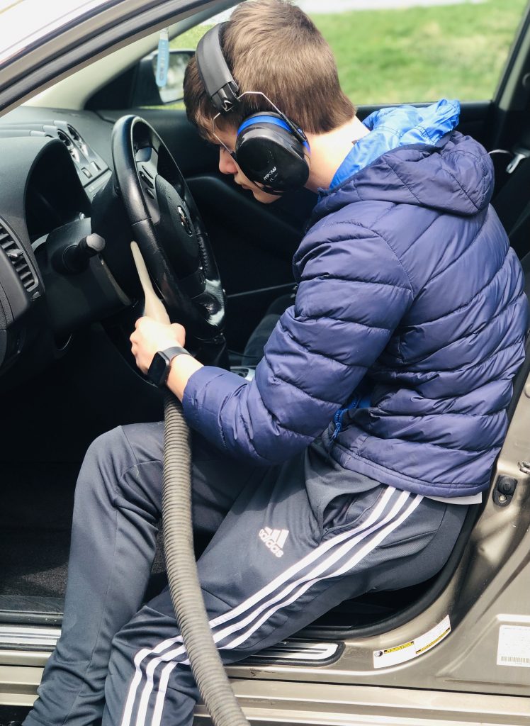 boy vacuuming out a car