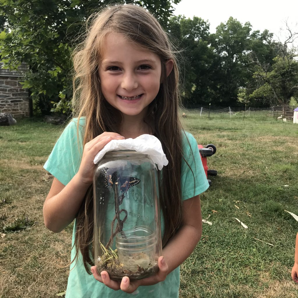 girl showing jar of butterflies