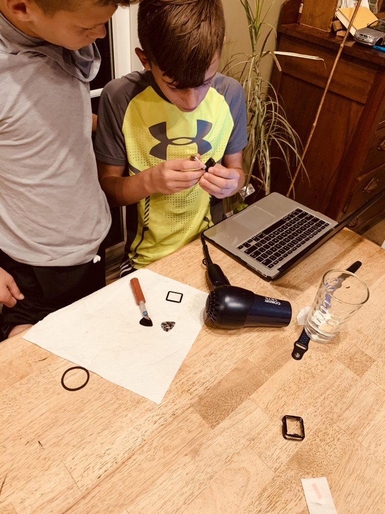 two boys at a computer taking something apart